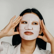 etalle de una modelo aplicando una mascarilla coreana de hidrogel transparente sobre la piel limpia e iluminada