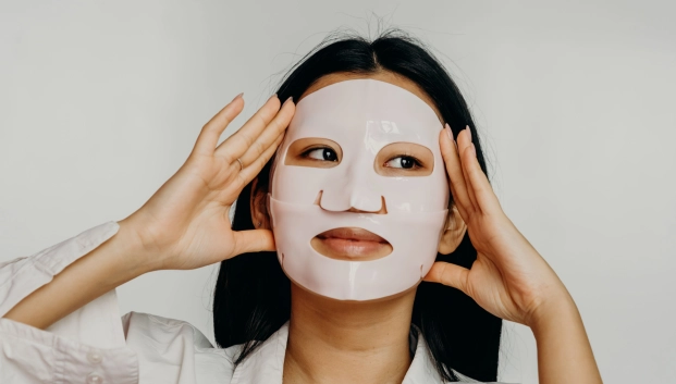 etalle de una modelo aplicando una mascarilla coreana de hidrogel transparente sobre la piel limpia e iluminada